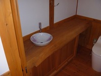 杉の無垢材で造られたトイレのカウンターには陶器の手洗器がよく合います。